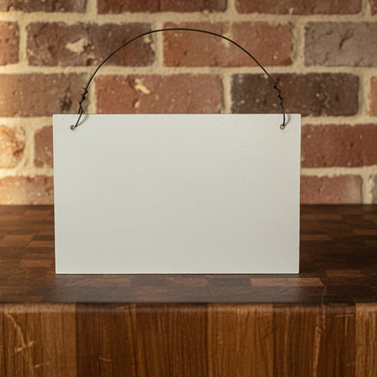 Blank white sign on a wooden surface with a brick wall background