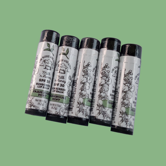 Five lip balm tubes with labels on a white background