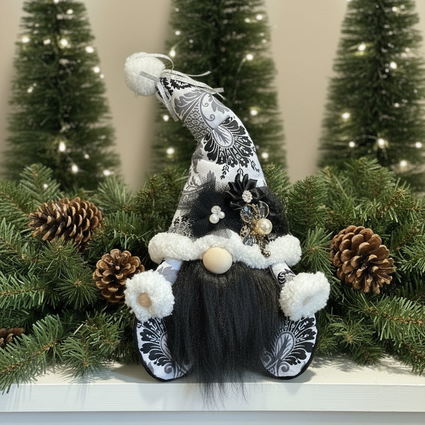 Decorative gnome with black and white hat and outfit, surrounded by pine cones and greenery.