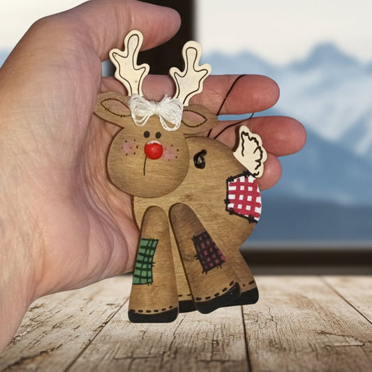 Hand holding a wooden reindeer ornament with a plain background