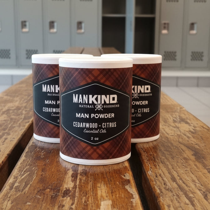 Three containers of Hankind Man Powder on a green surface with a brick wall background.