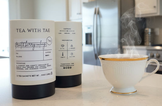 Two packages of 'Tea with Tae' tea and a teacup on a kitchen counter.