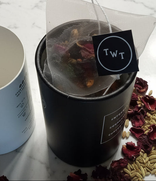 Tea packaging with dried herbs on a marble surface