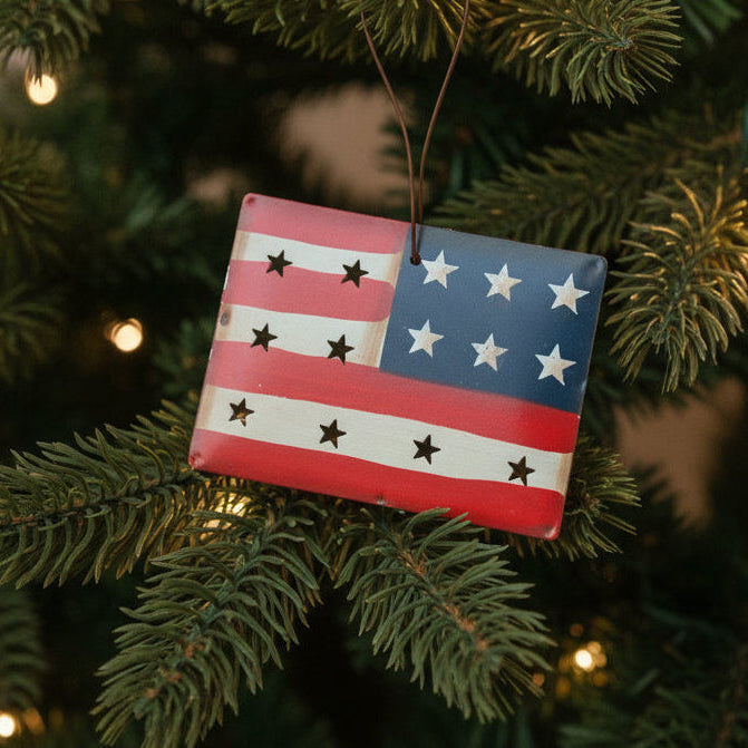 Small American flag ornament hanging on a Christmas tree.