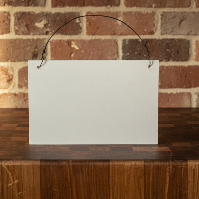 Blank white sign on a wooden surface with a brick wall background