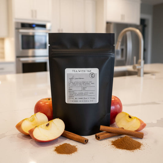 Black tea packaging with apples and cinnamon on a kitchen counter