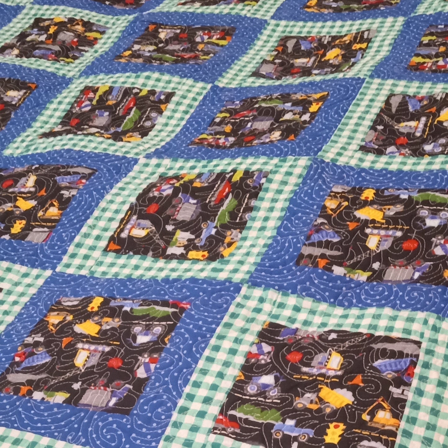 Quilt with train-themed blocks on a blue and green checkered background