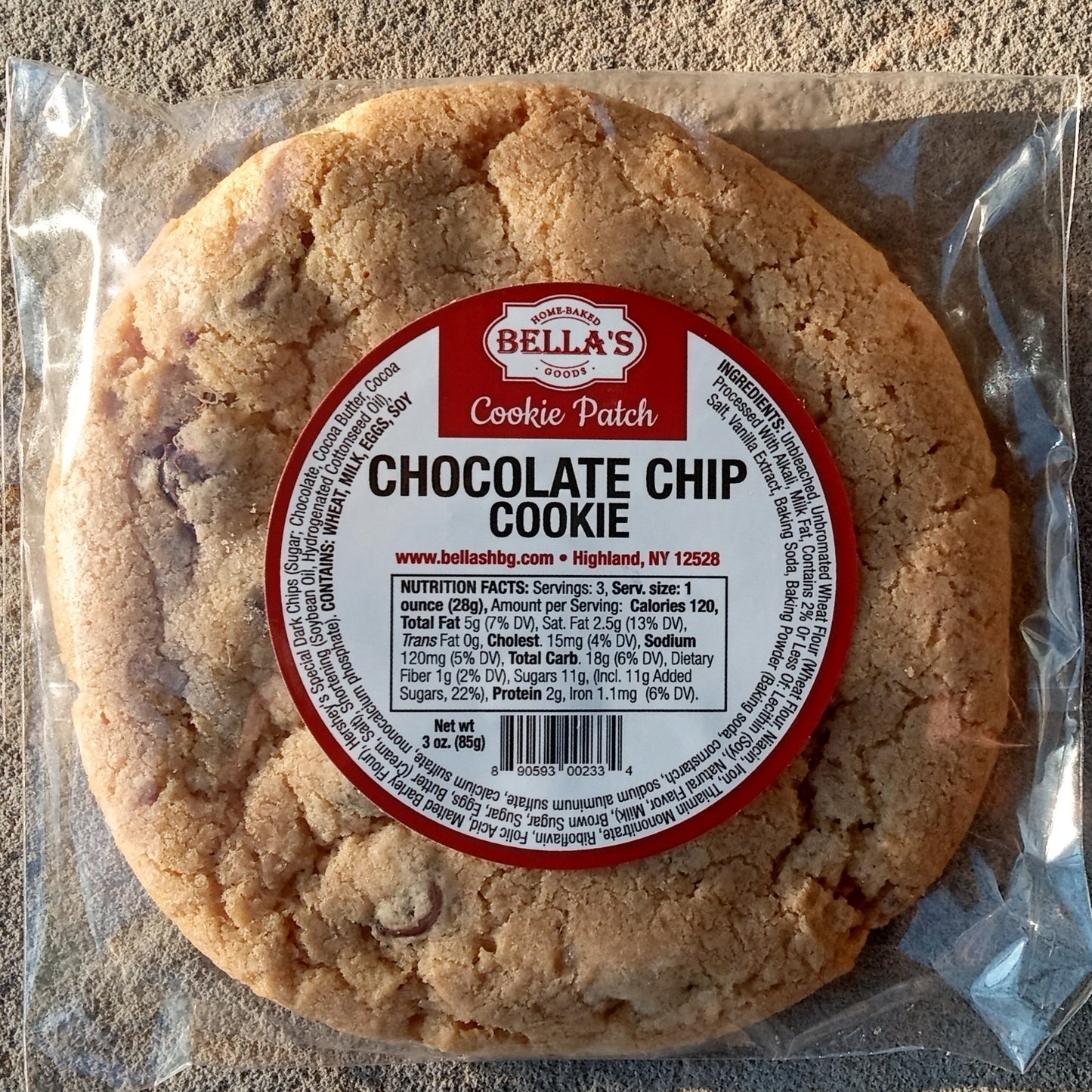 Chocolate chip cookie in packaging on a sandy surface