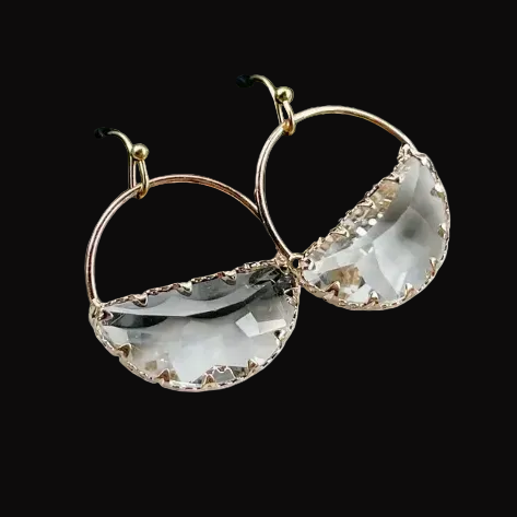 Gold hoop earrings with clear crystal stones on a gray background