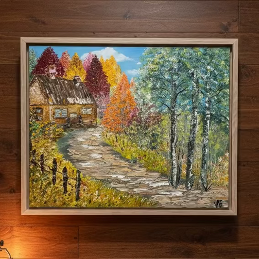 Framed painting of a rustic cabin in a forest with autumn colors on a wooden wall.