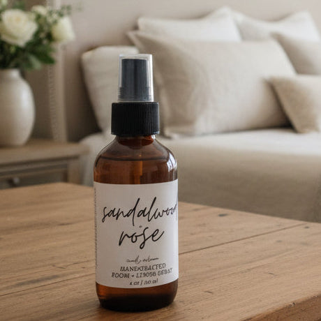 Bottle of sandalwood rose diffuser on a wooden nightstand in a bedroom.