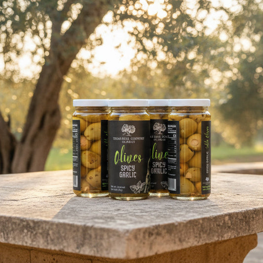 Jars of olives on a stone table with olive trees in the background