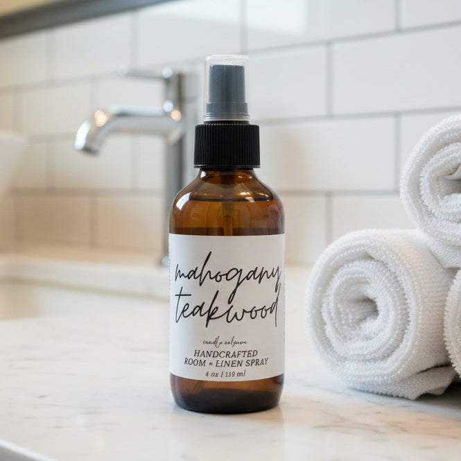 Bottle of 'Teakwood' cologne on a bathroom counter with rolled towels.