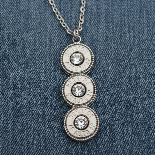 Silver necklace with three circular pendants on a stone surface