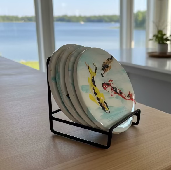 Set of decorative plates in a stand on a kitchen counter with a view of a lake.