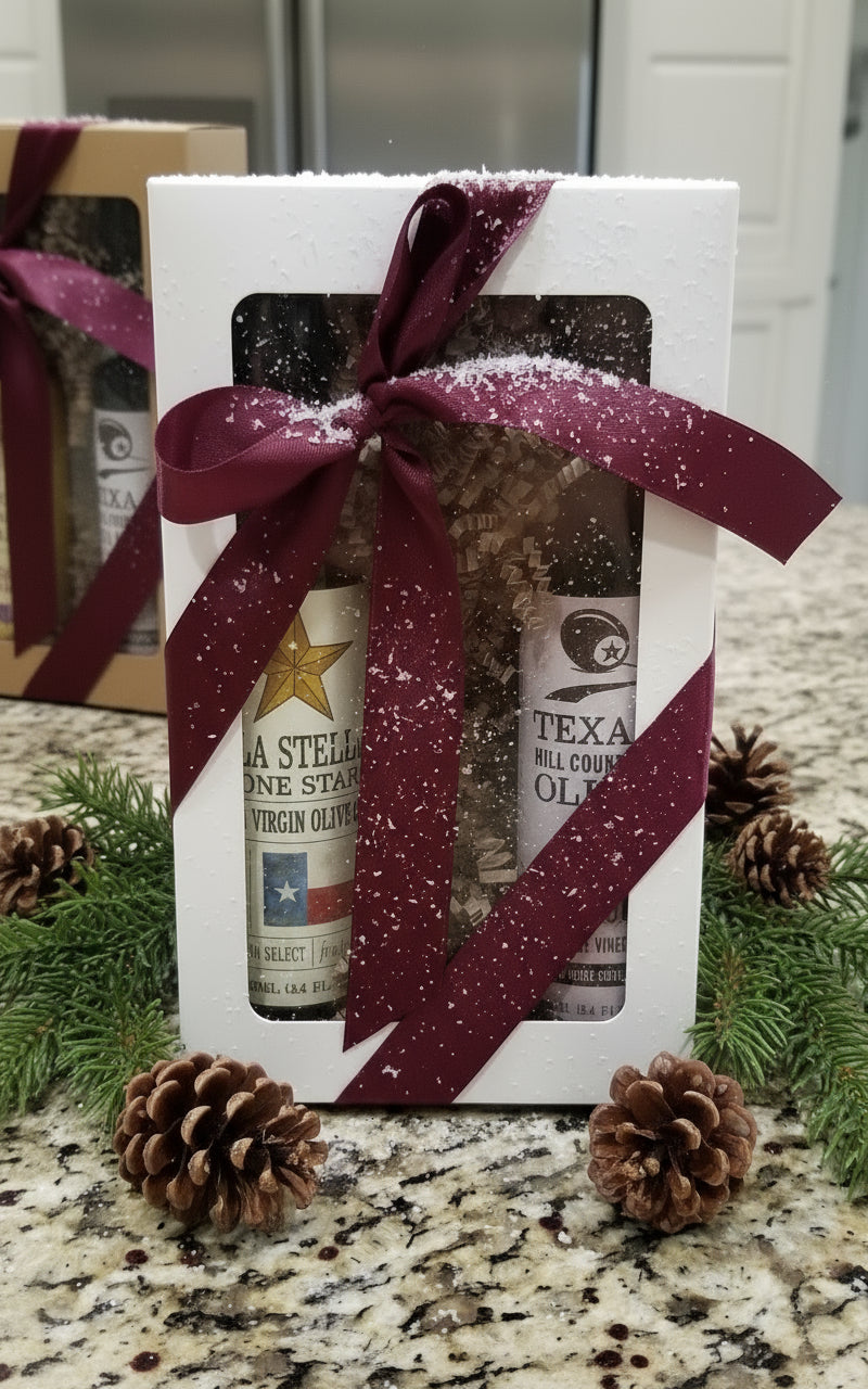 Gift box with two bottles of olive oil and a purple ribbon on a wooden surface