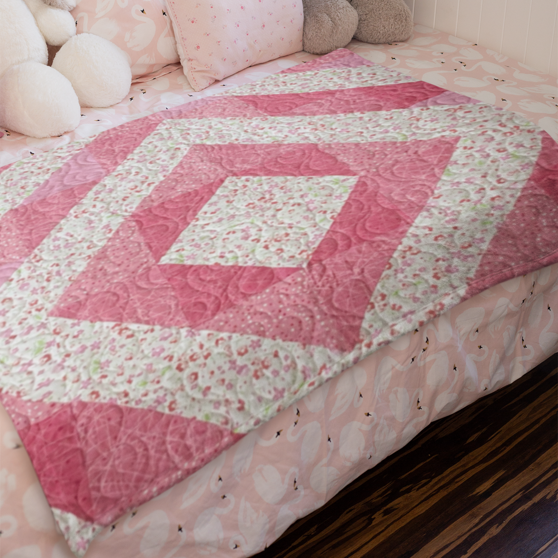 Pink quilt with floral patterns on a bed with white pillows and a stuffed bunny.