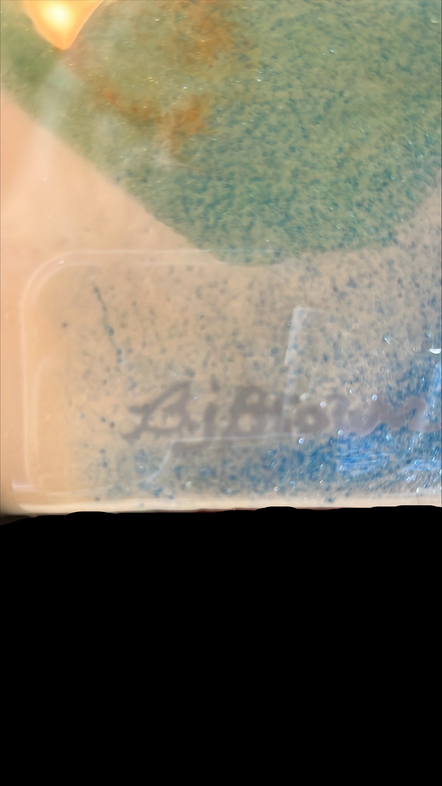 Clear plastic container with a brand name on a reflective surface