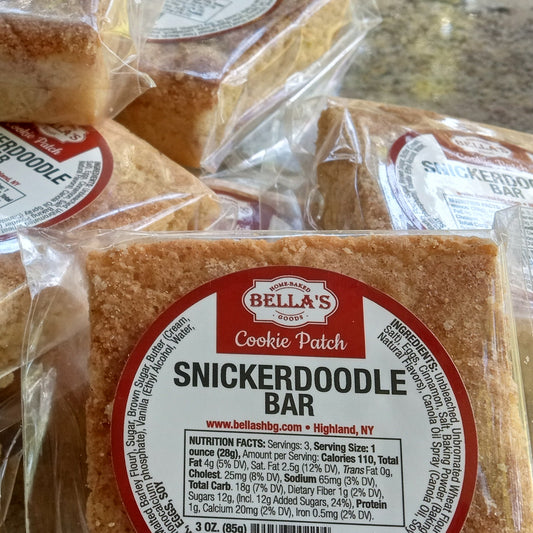 Bella's Snickerdoodle Bars in clear packaging with red labels on a marble surface.