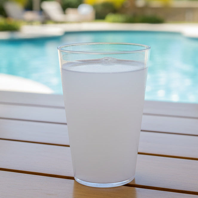 Clear plastic cup with white liquid on a dark surface