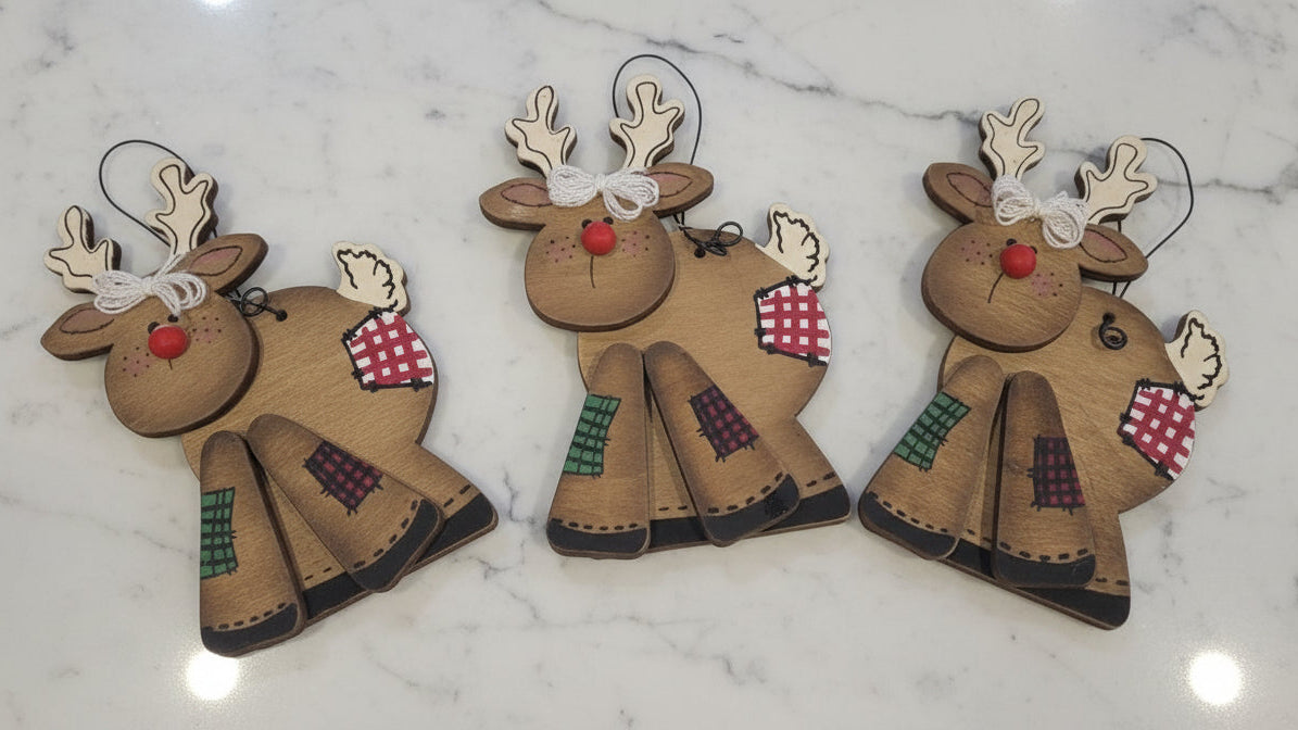 Three reindeer ornaments with red noses and green scarves on a white background