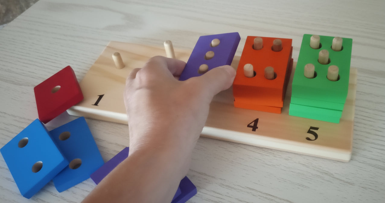 Hand interacting with colorful wooden blocks on a wooden board with numbers.