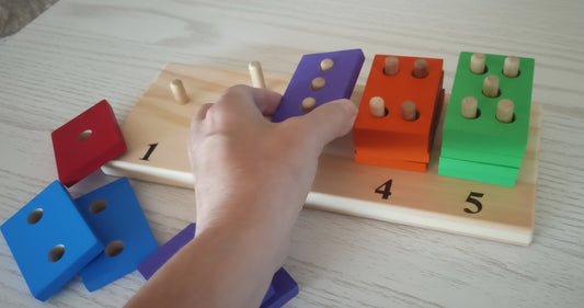 Hand interacting with colorful wooden blocks on a wooden board with numbers.